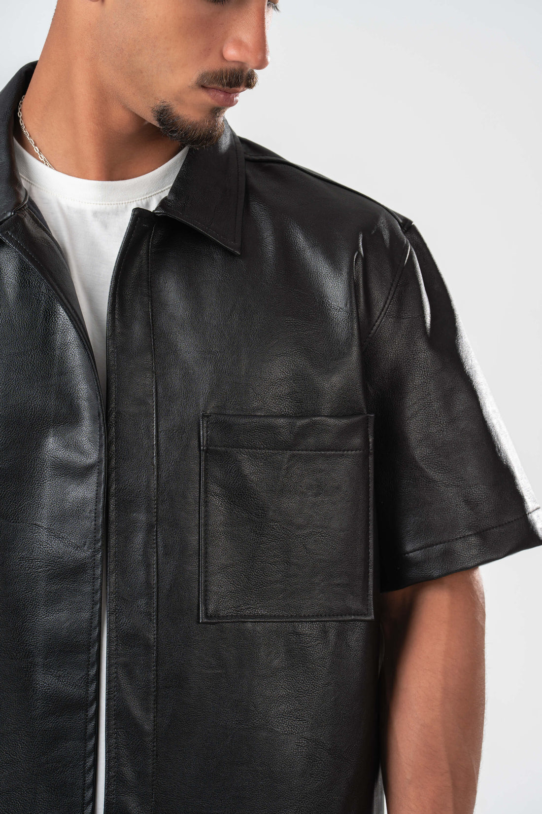 Man wearing a black leather shirt over a white t-shirt on a white background