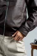 Person wearing a brown leather jacket with a neutral background