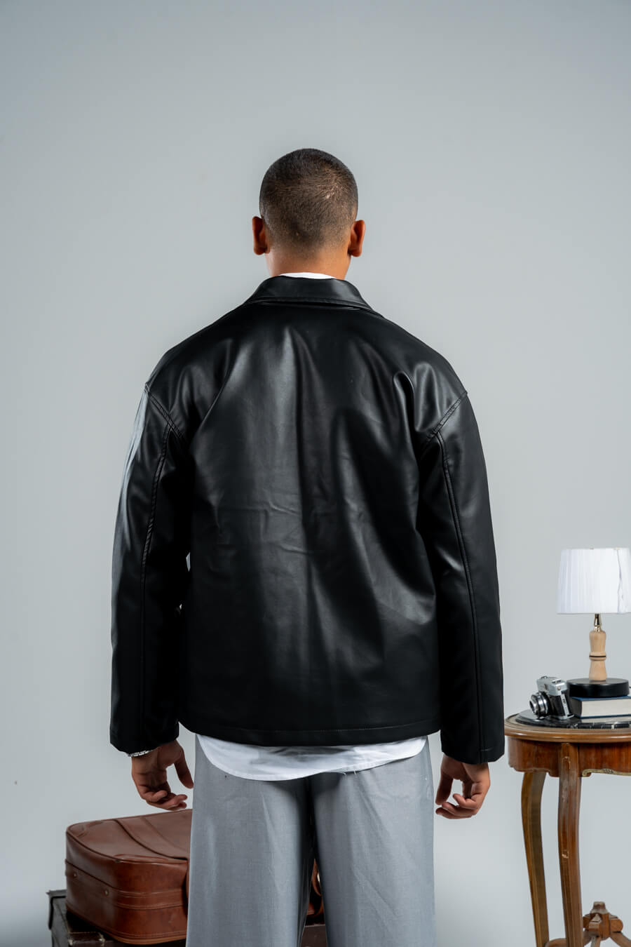 Man wearing a black leather jacket from behind on a plain background