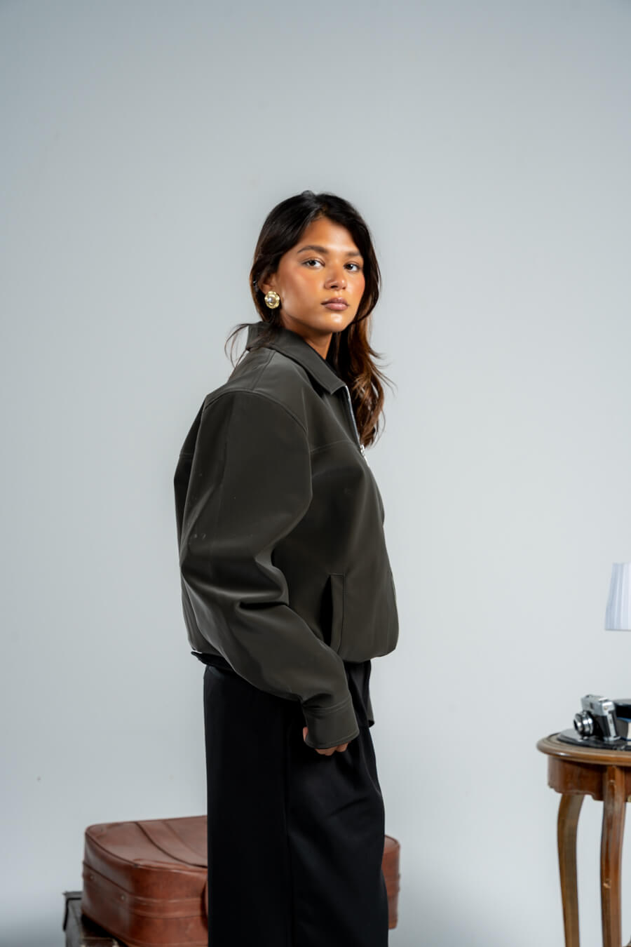 Woman wearing a green jacket and black pants against a plain background