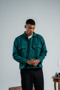Man wearing a green jacket and black pants against a plain background