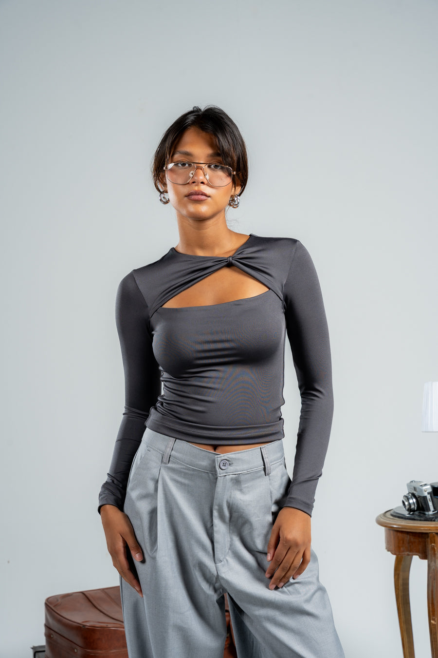 Woman wearing a gray long-sleeve top and light gray pants against a plain background