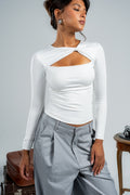 Woman wearing a white long-sleeve top with cut-out design and gray pants against a plain background