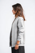 Woman wearing a light gray cardigan over a black top on a white background