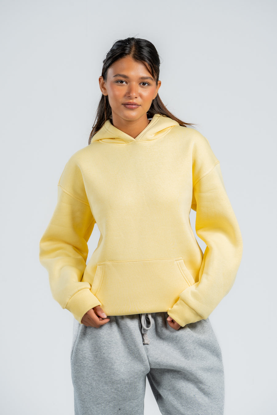 Two people wearing matching yellow hoodies and gray pants against a plain background