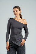 Woman wearing a gray one-shoulder top against a plain background