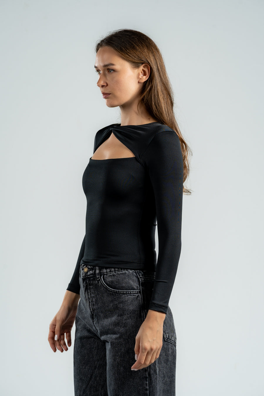 Woman wearing a black long-sleeve top with a unique design on a light gray background