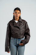 Person wearing a brown leather jacket and blue jeans against a plain background