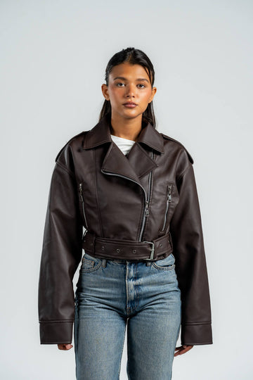 Person wearing a brown leather jacket and blue jeans against a white background