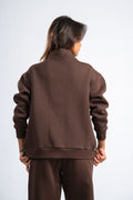 Person wearing a brown tracksuit against a white background