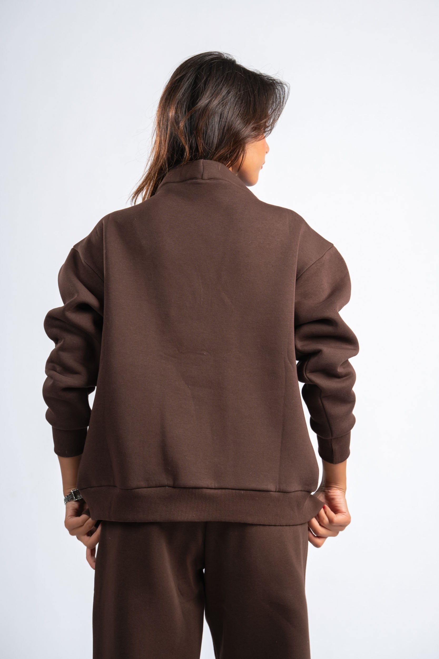 Person wearing a brown tracksuit against a white background