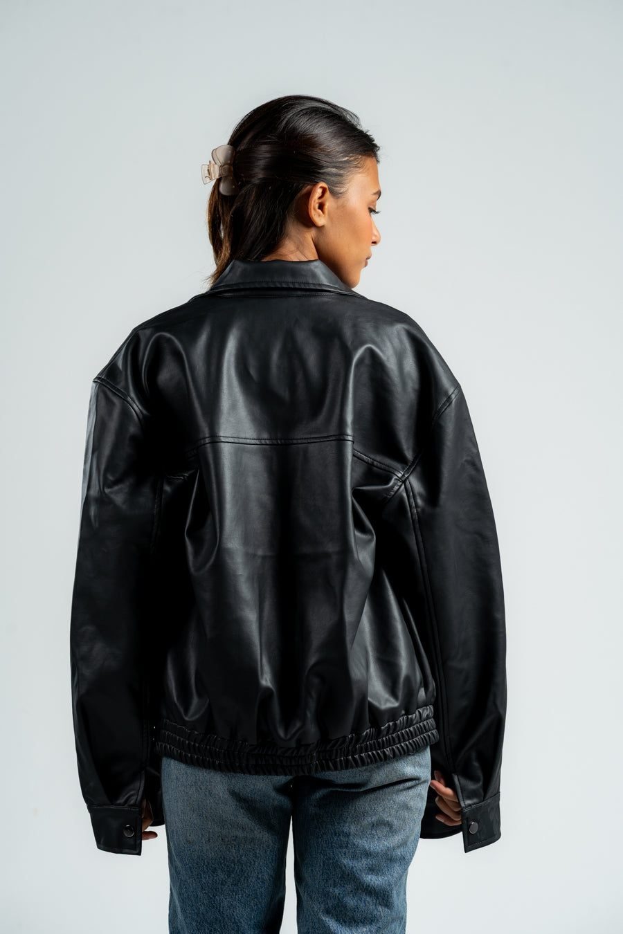 Person wearing a black leather jacket on a plain background