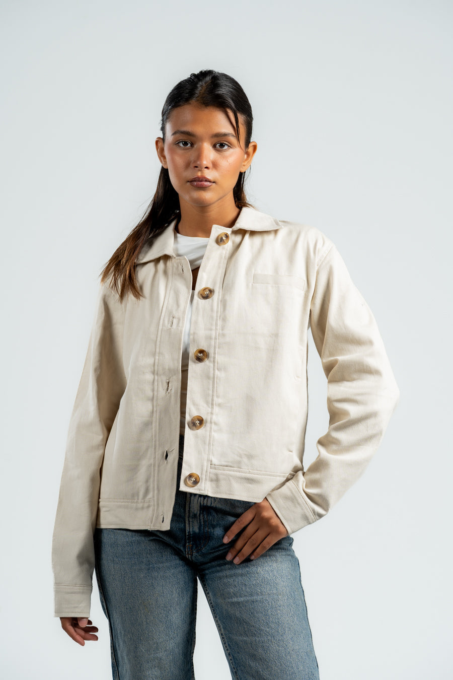 Woman wearing a beige jacket with button details on a white background