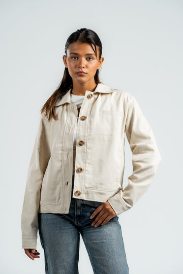 Woman wearing a beige jacket with button details on a white background