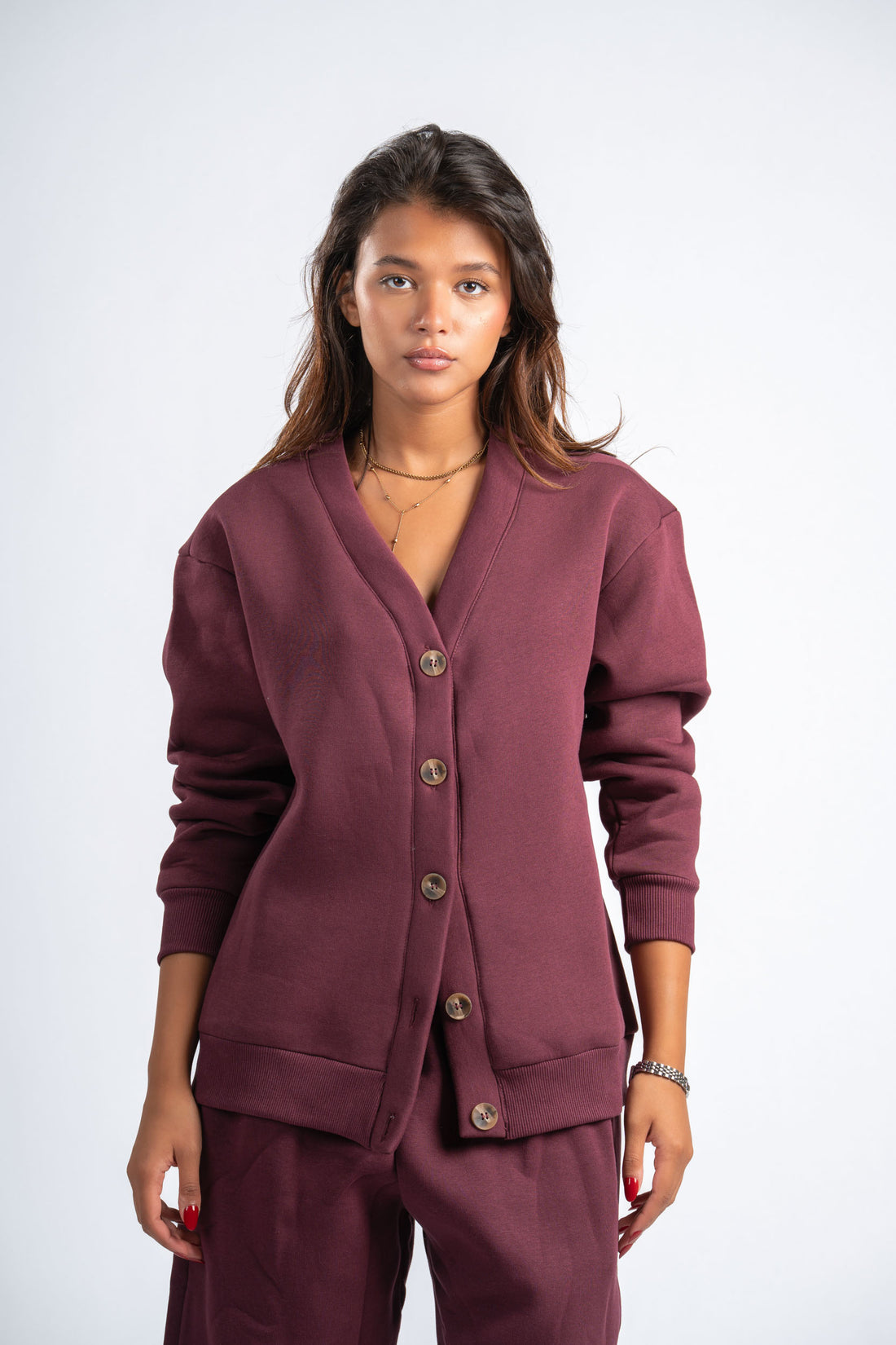 Woman wearing a maroon cardigan and pants on a white background