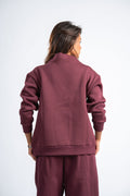Person wearing a maroon tracksuit on a white background