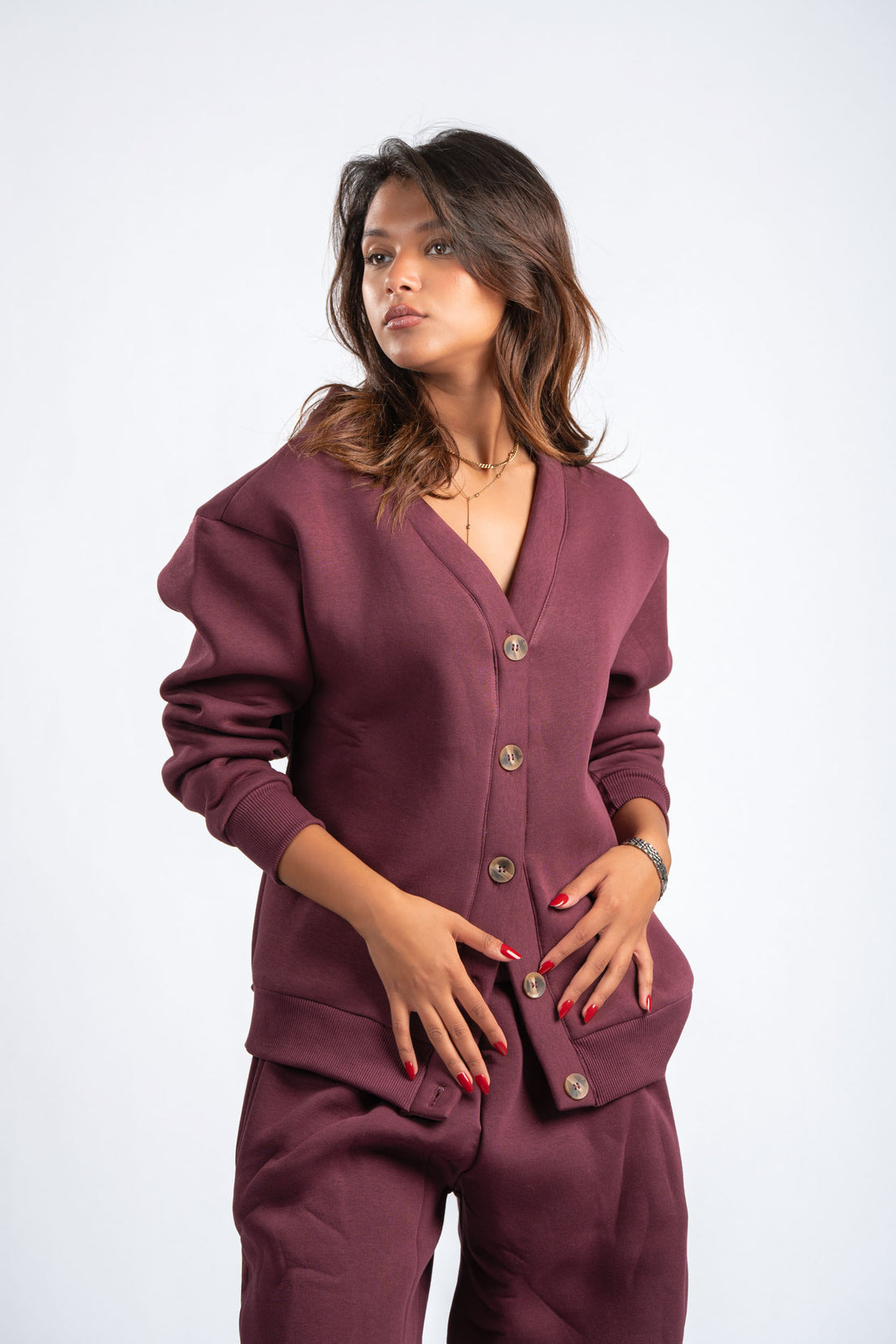 Woman wearing a maroon cardigan and pants on a white background