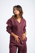 Woman wearing a maroon outfit with button details on a white background