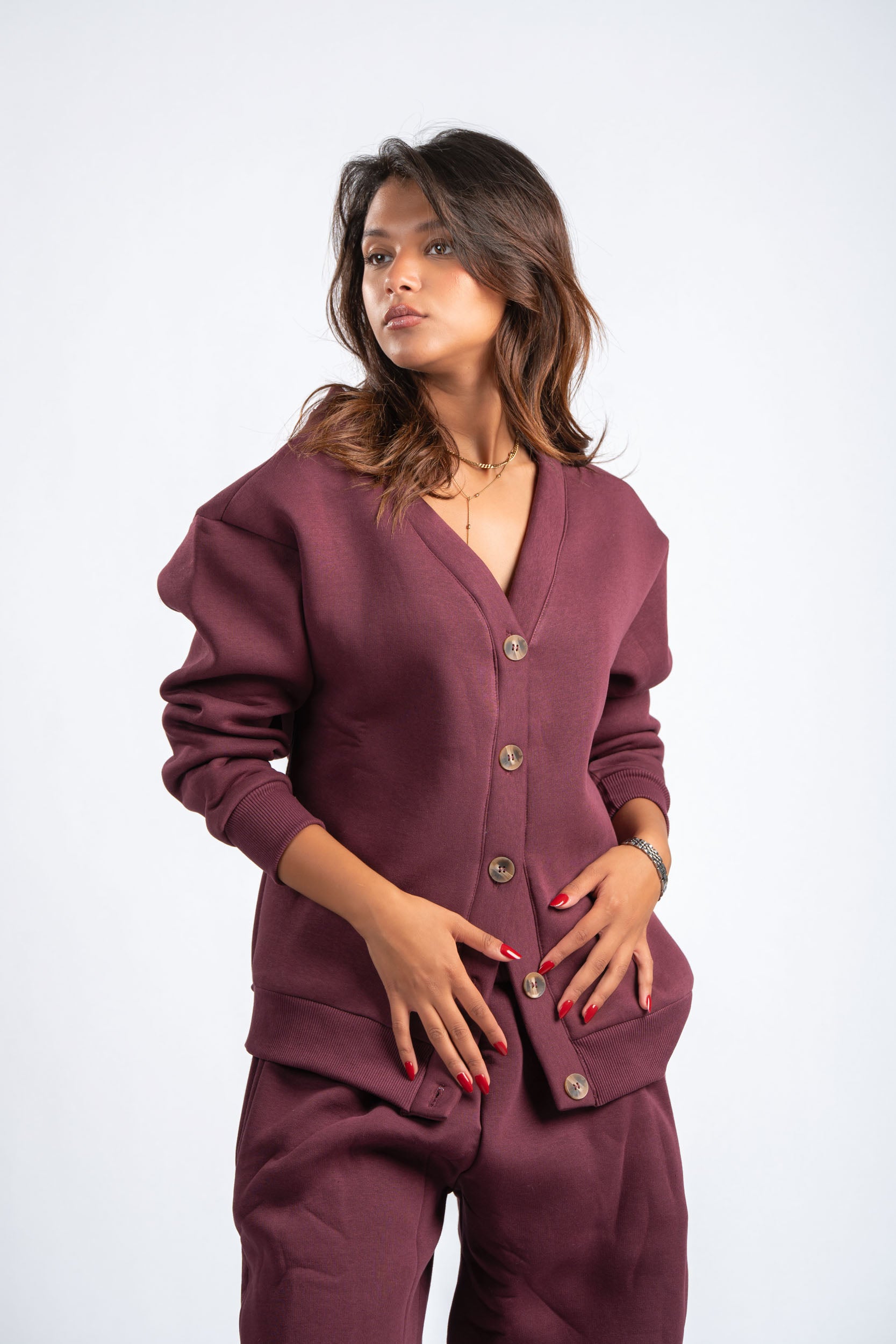 Woman wearing a maroon outfit with button details on a white background