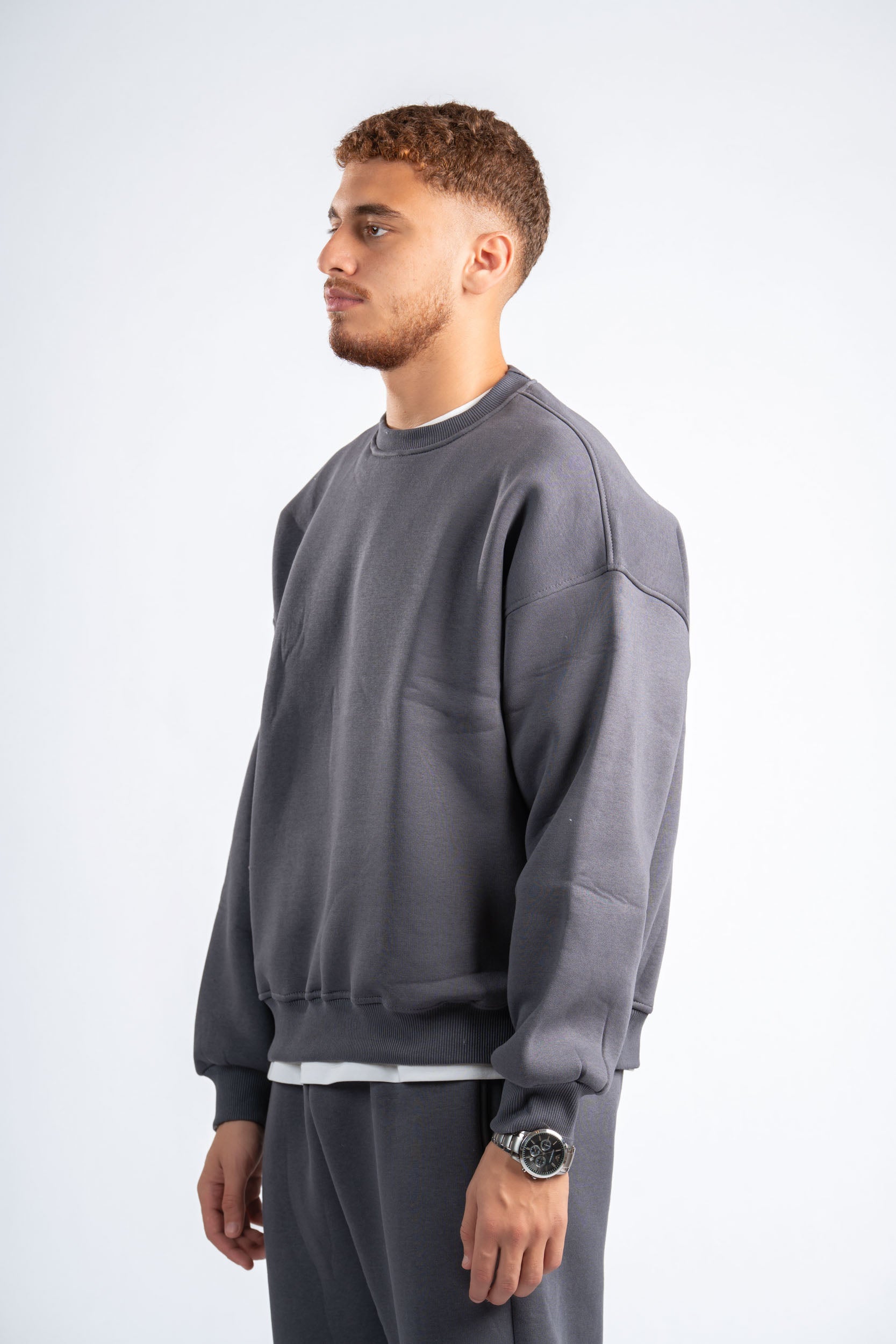 Man wearing a gray sweatshirt and pants on a white background