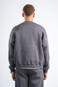 Person wearing a gray sweatshirt and pants on a white background