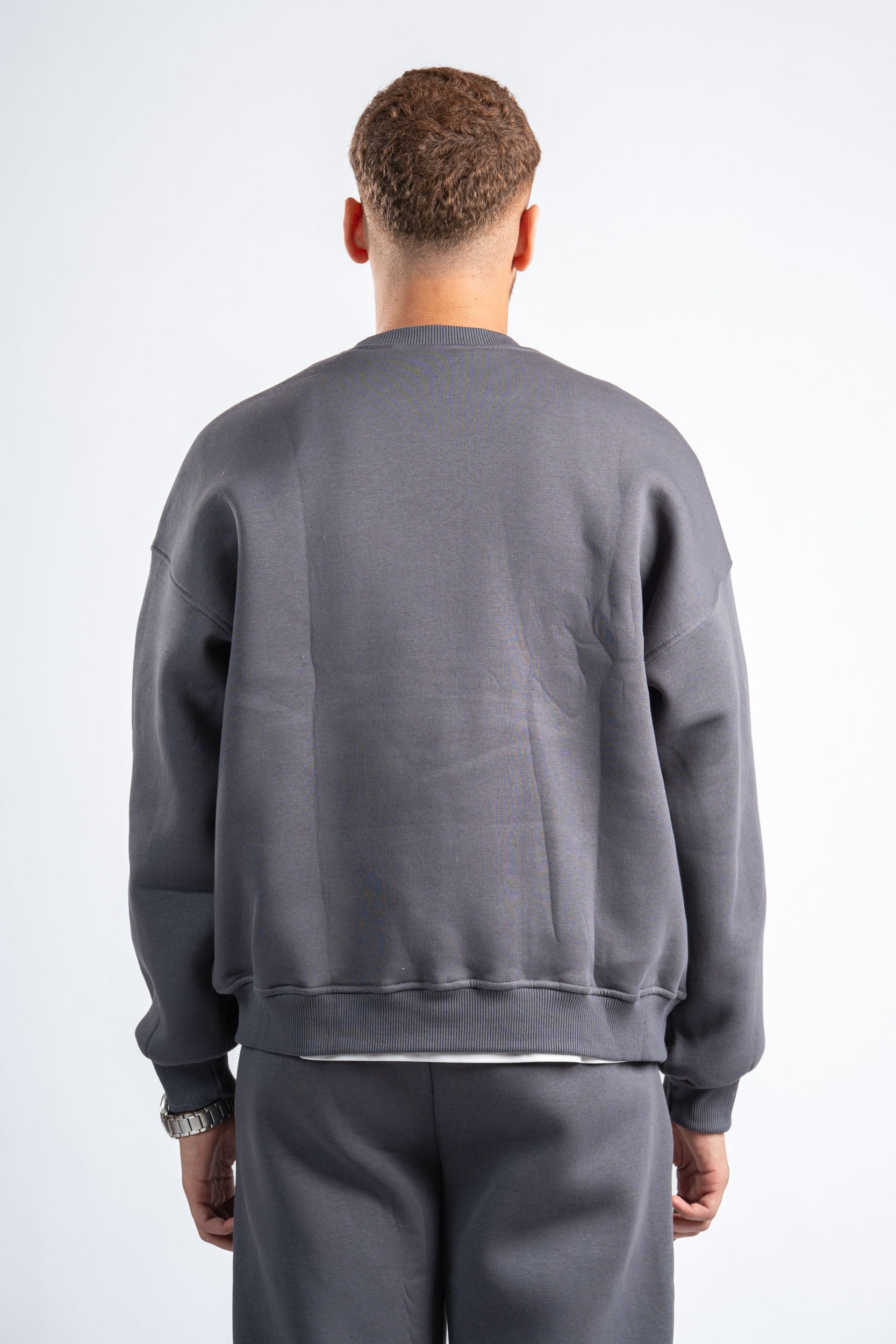 Person wearing a gray sweatshirt and pants on a white background