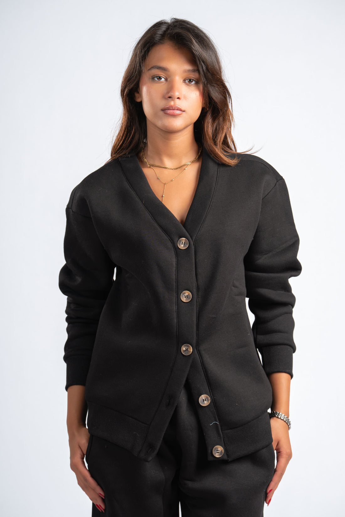 Woman wearing a black cardigan with buttons on a white background