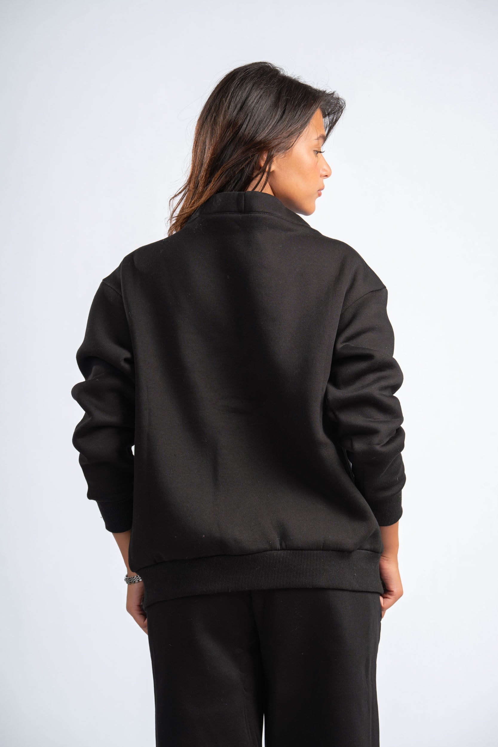 Person wearing a black jacket and pants on a white background
