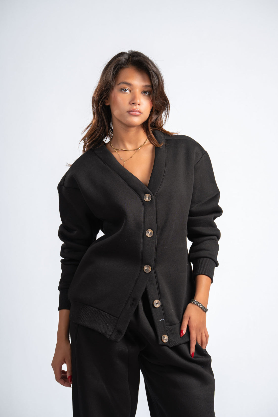 Woman wearing a black cardigan with buttons on a white background