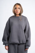 Person wearing a gray sweatshirt and pants on a white background