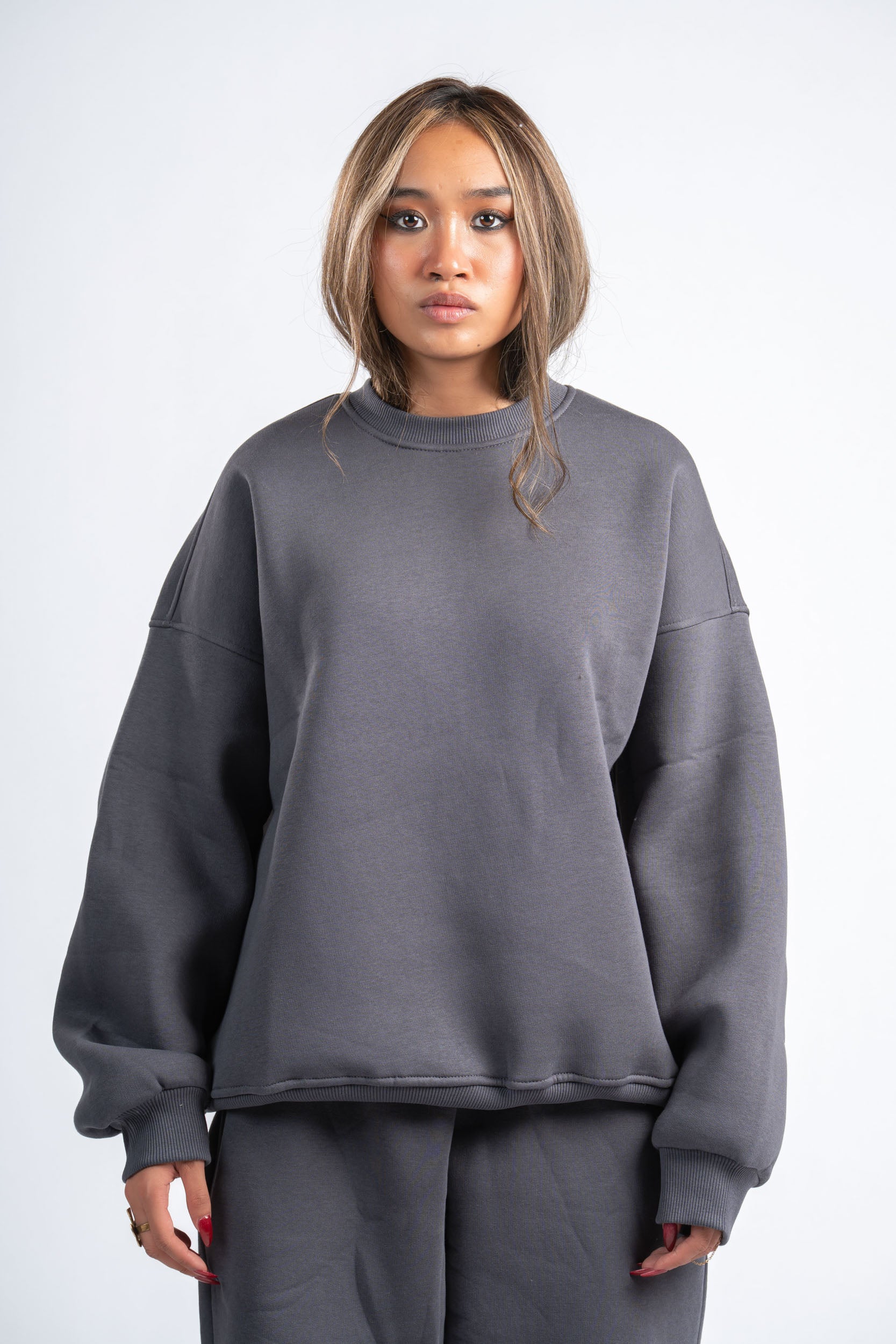 Person wearing a gray sweatshirt and pants on a white background
