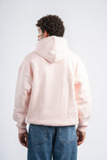 Person wearing a light pink hoodie and blue jeans on a white background