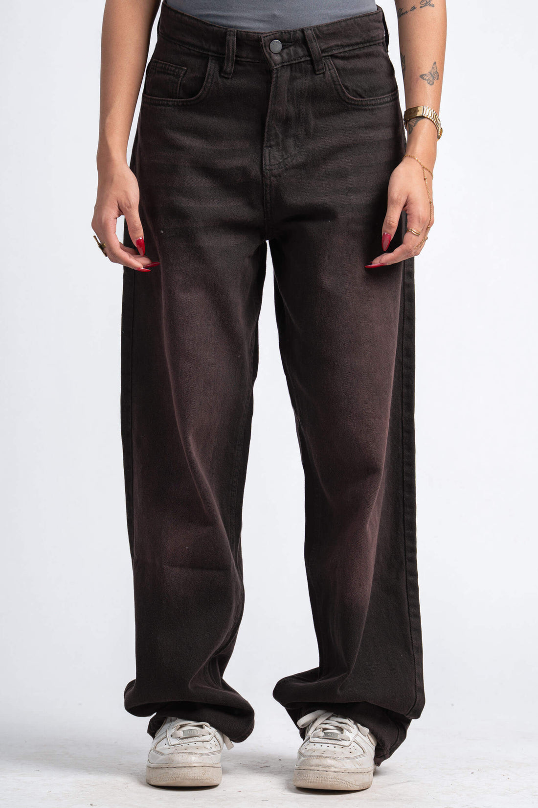Person wearing dark brown wide-leg jeans on a white background
