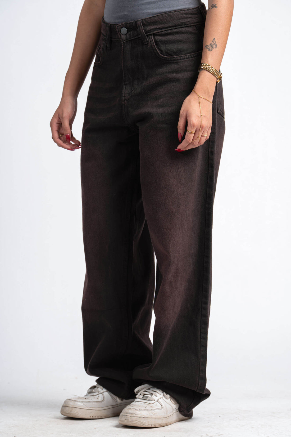 Person wearing dark brown wide-leg jeans on a white background