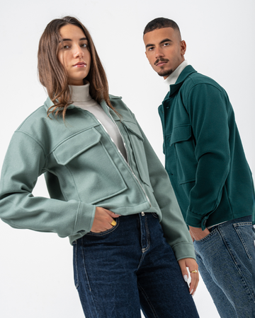 Two people wearing jackets and jeans on a white background