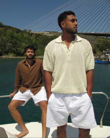 Two men on a boat with a bridge and water in the background