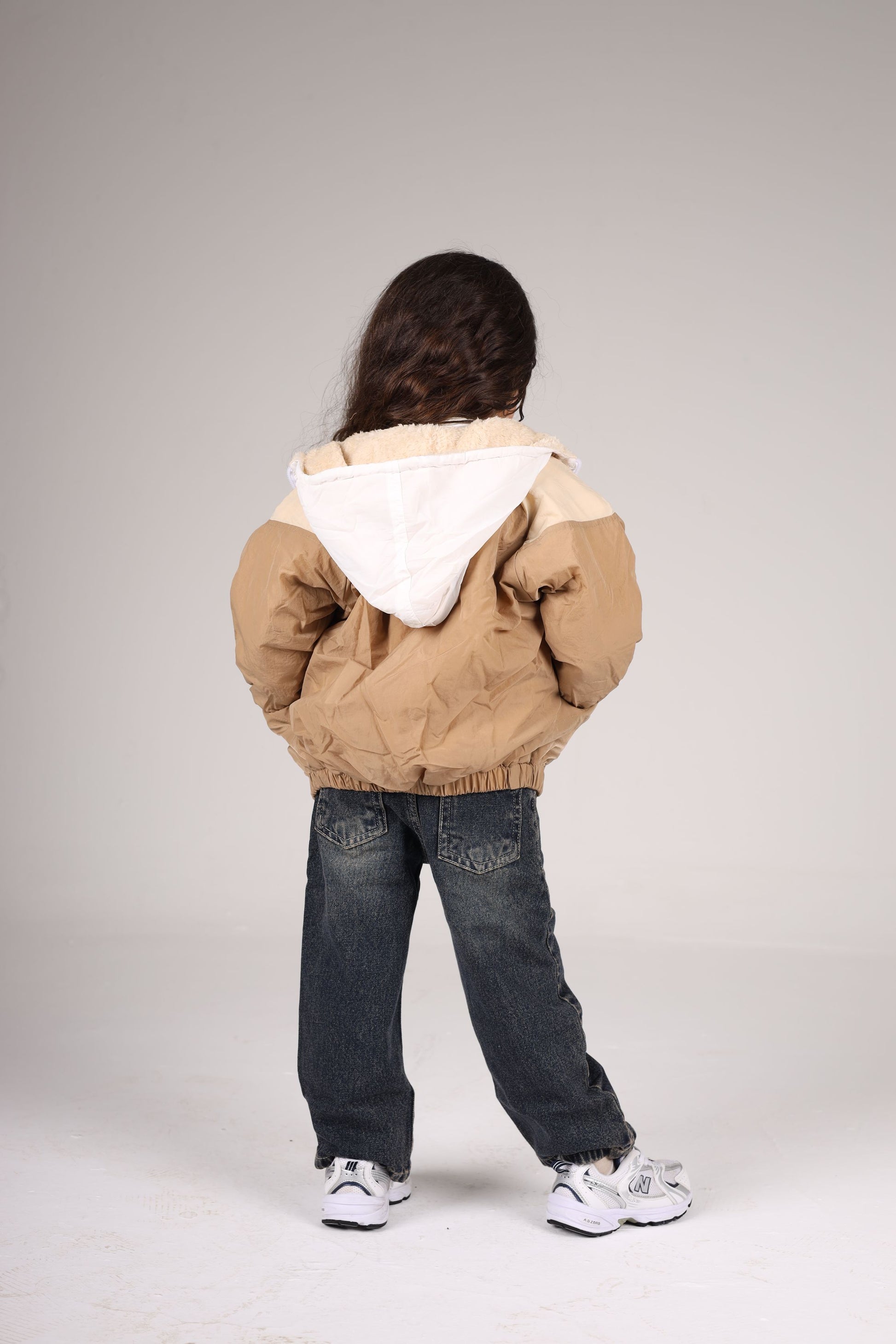 Person wearing a beige and white jacket on a plain background