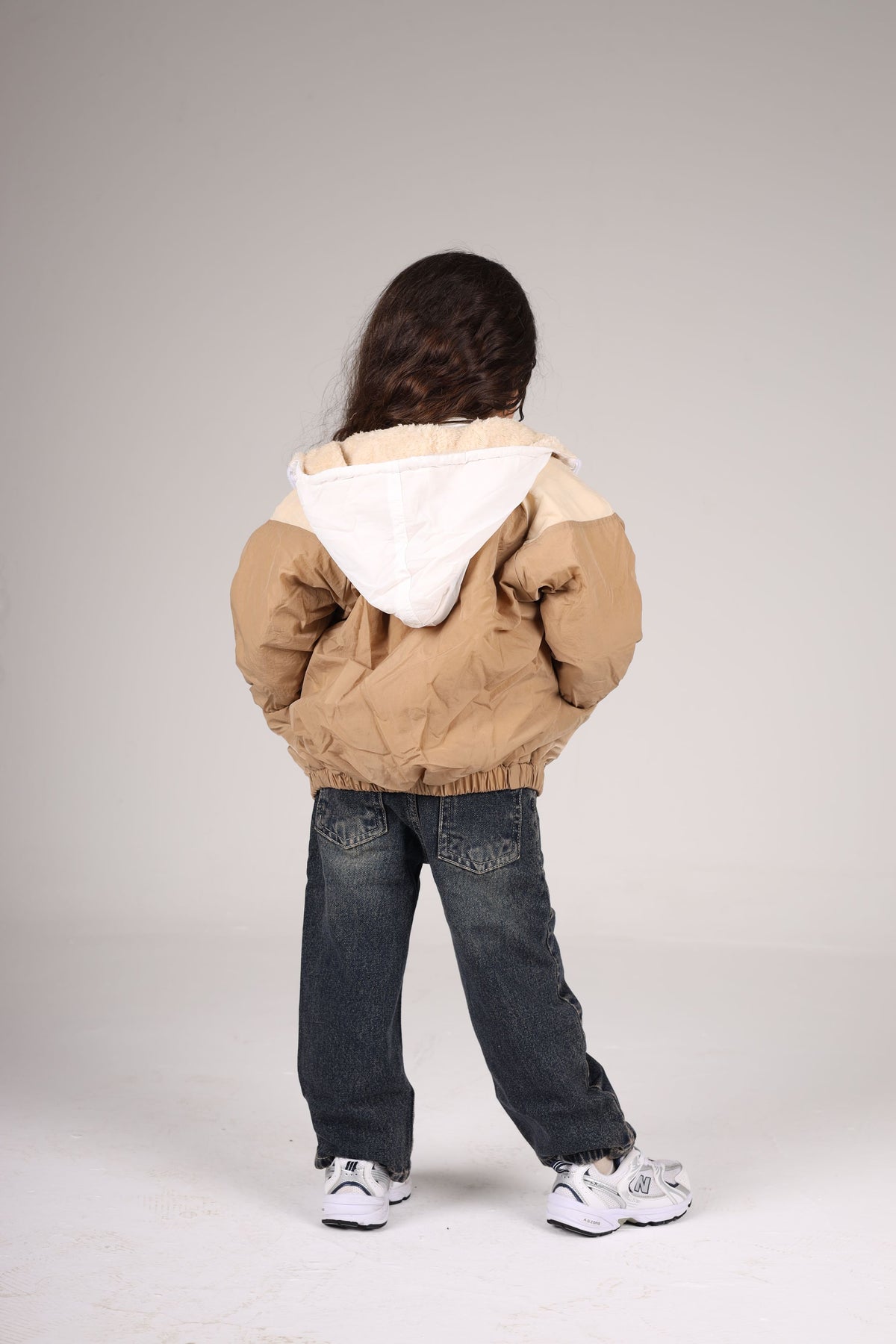 Person wearing a beige and white jacket on a plain background