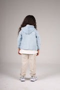 Child wearing a light blue denim jacket on a plain background