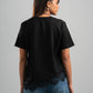 Person wearing a black oversized t-shirt and blue jeans on a gray background