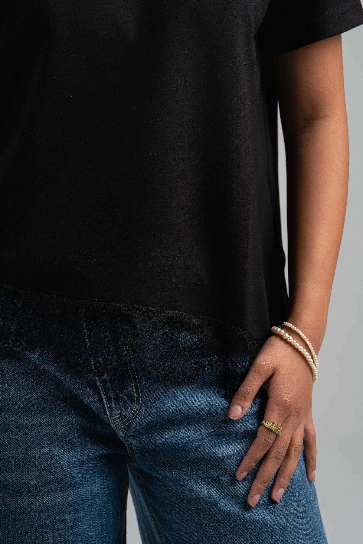Person wearing a black t-shirt and blue jeans with a neutral background