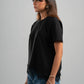 Woman wearing a black t-shirt and blue jeans against a gray background