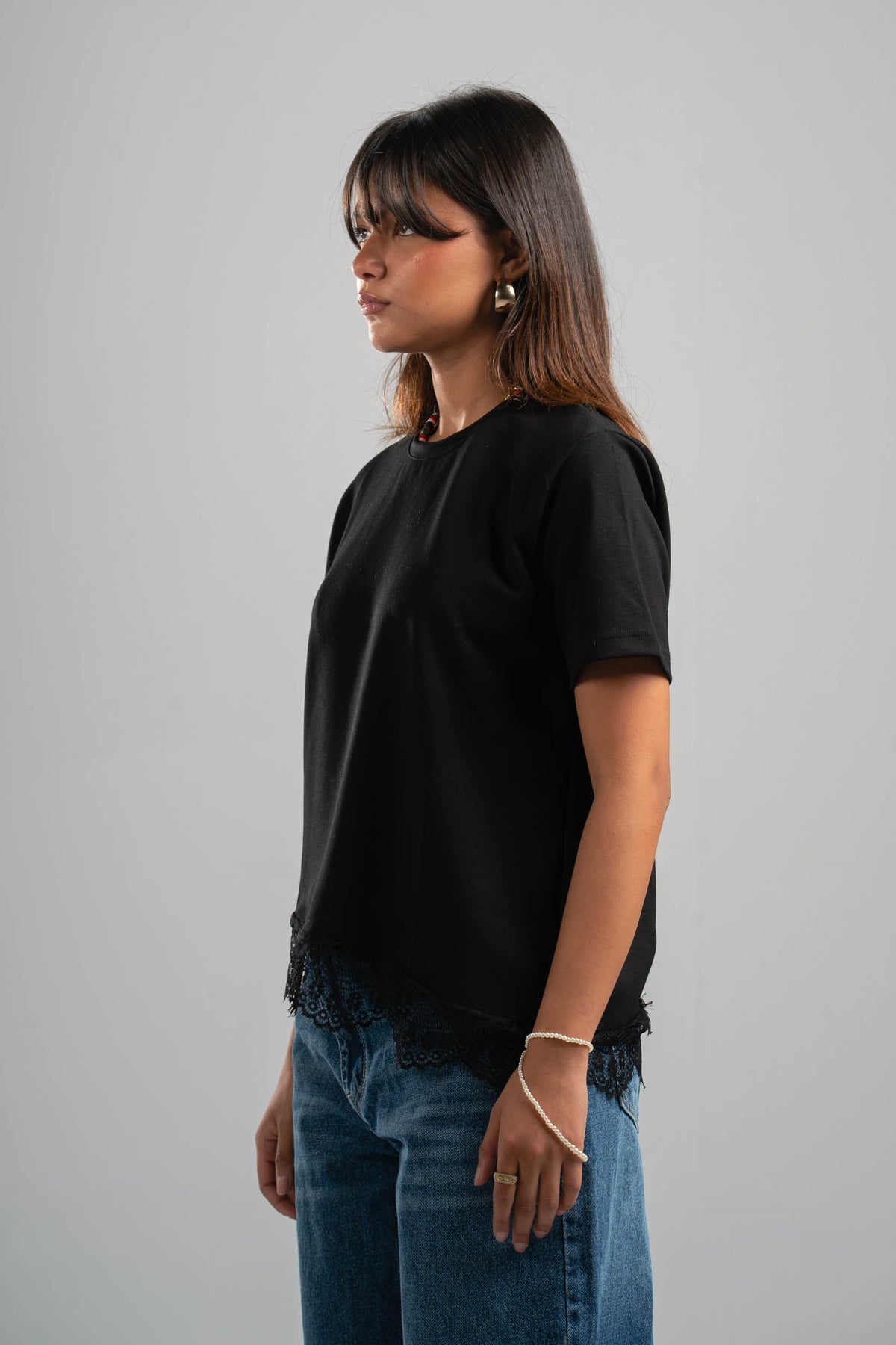 Woman wearing a black t-shirt and blue jeans against a gray background