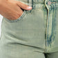 Close-up of green denim jeans with a pocket and button detail.