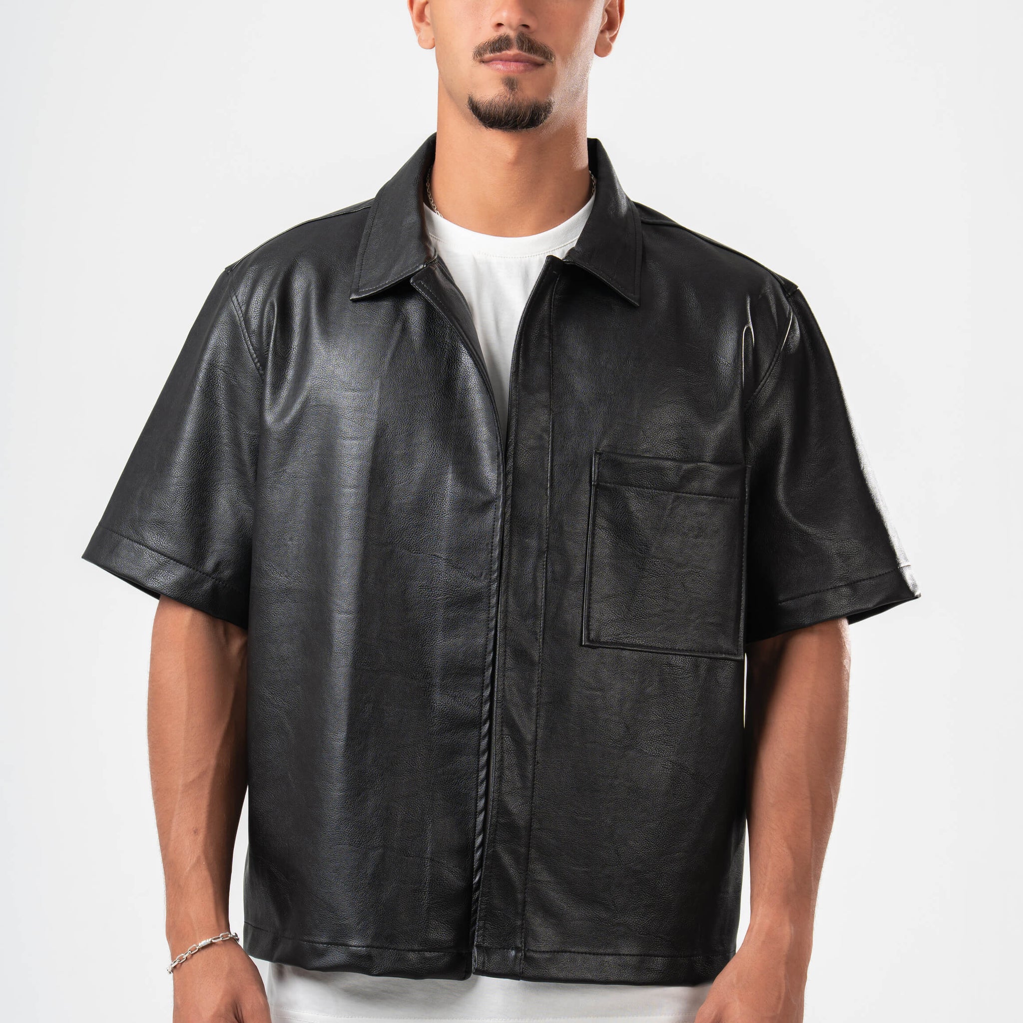 Man wearing a black leather shirt over a white t-shirt on a white background