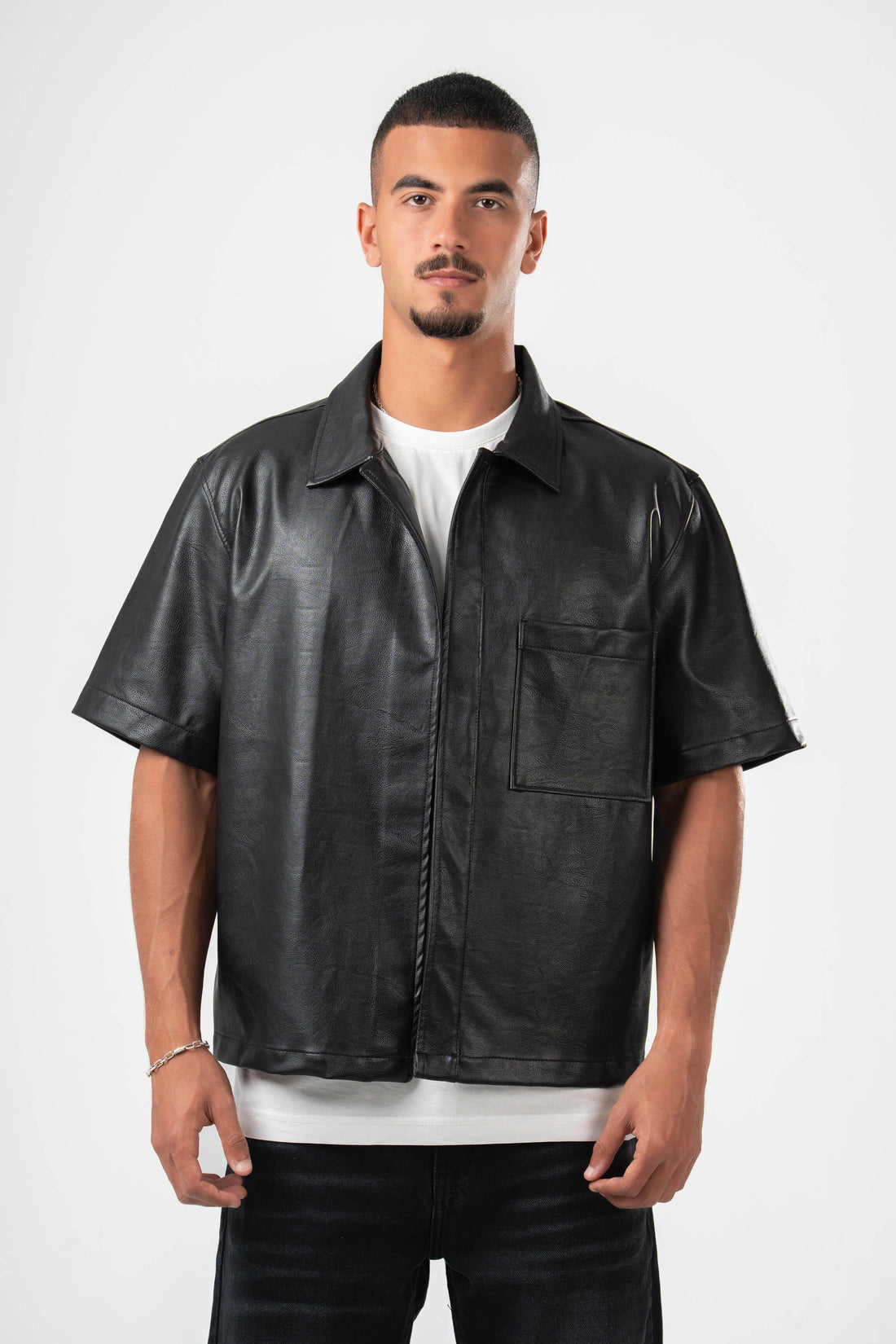 Man wearing a black leather shirt over a white t-shirt on a white background