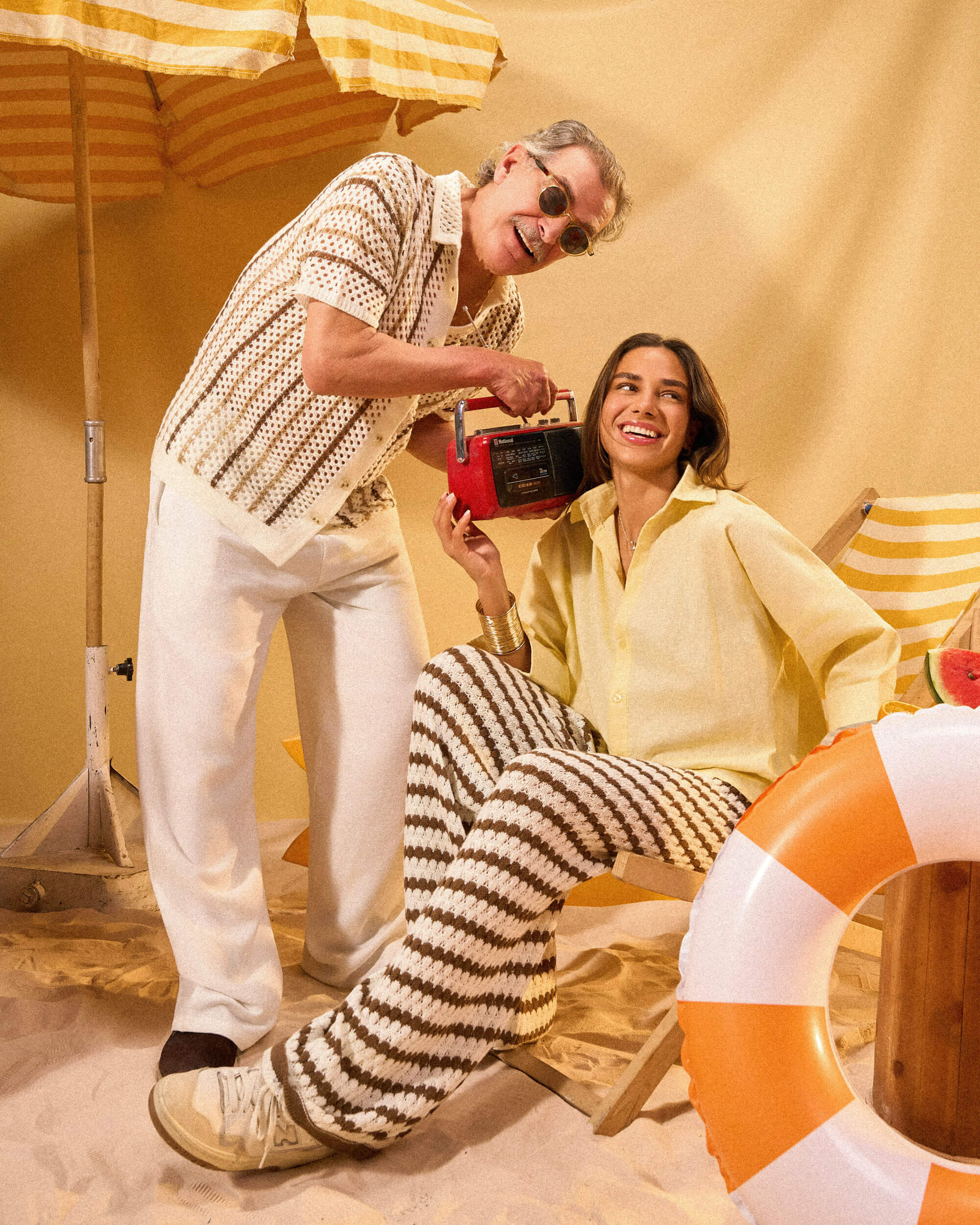 Man and woman in a beach setting with a radio and life buoy.