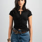 Woman wearing a black top and blue jeans with a belt on a plain background