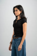 Woman wearing a black top and blue jeans on a gray background