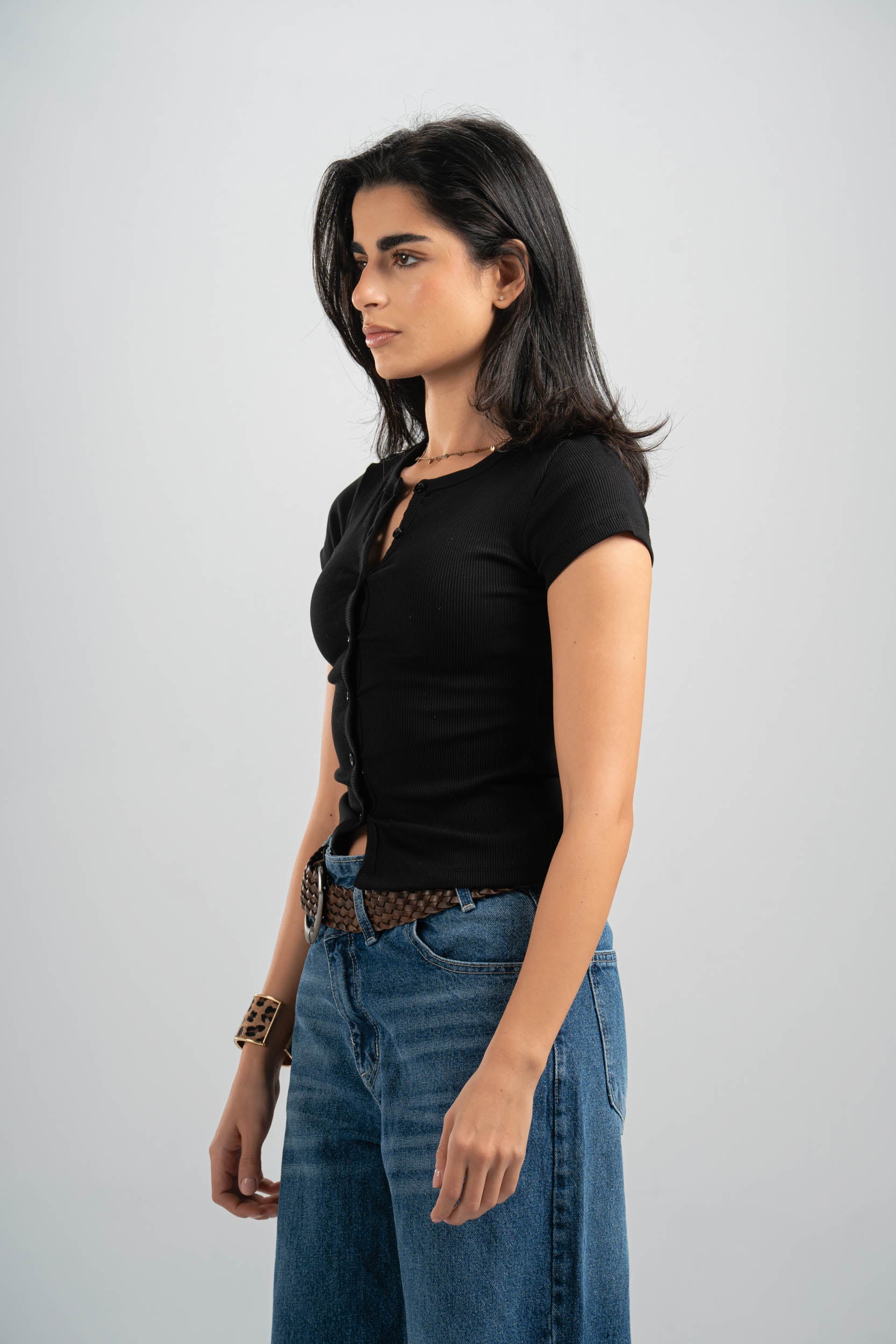 Woman wearing a black top and blue jeans on a gray background